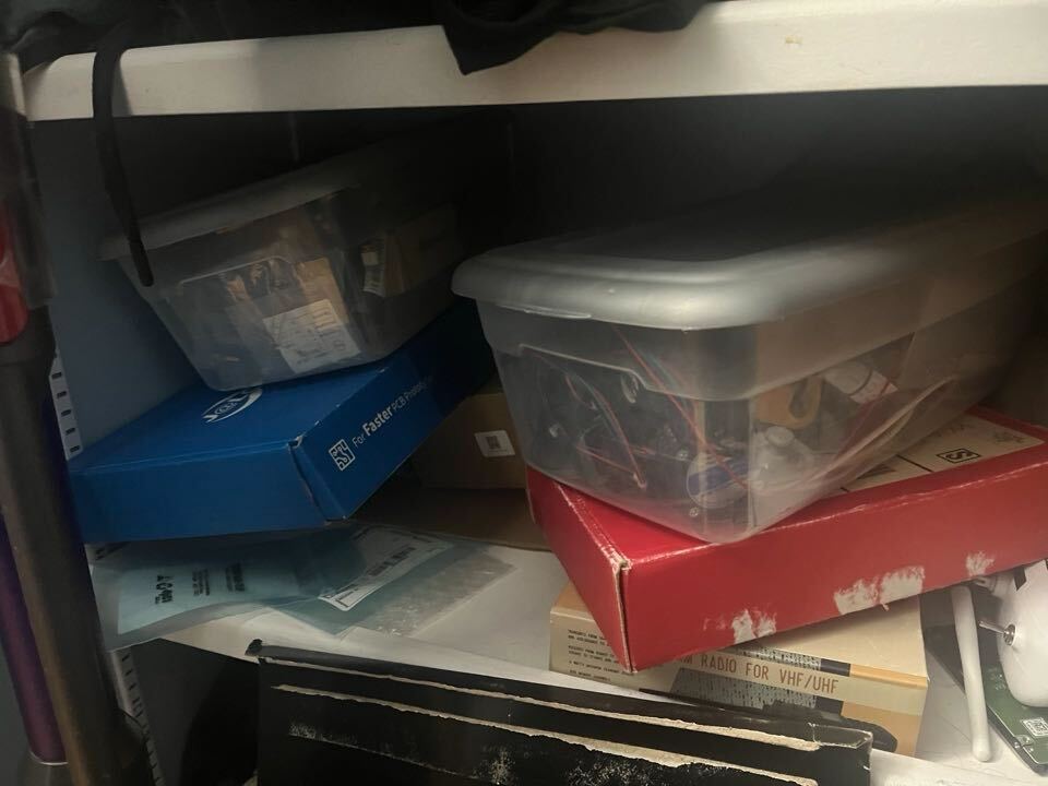 2 boxes of electronics sitting on a closet shelf