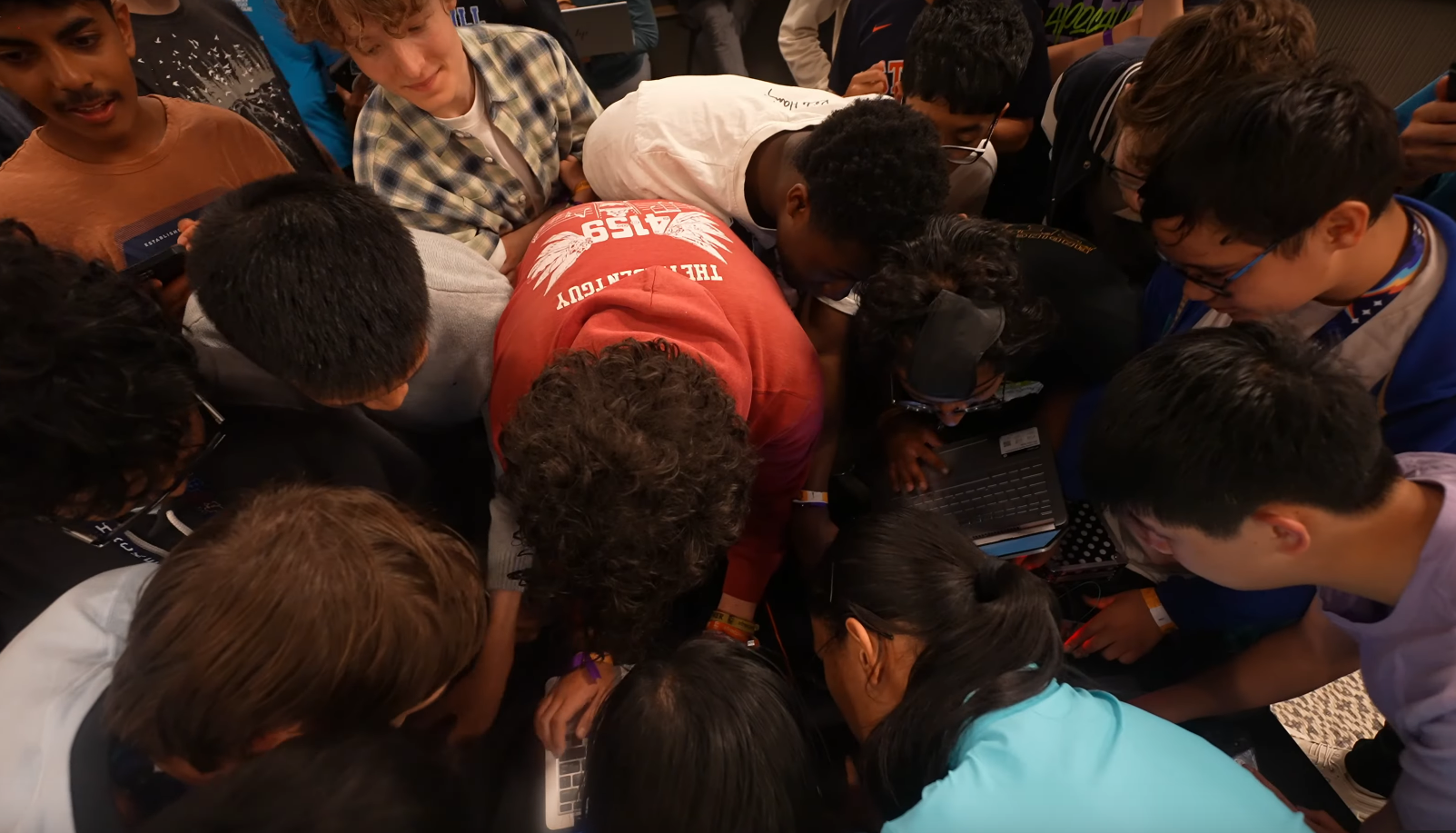 A bunch of teen hackers crowded around a table, trying to solve a puzzle
